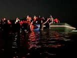 Moment packed small boat set for the UK gets caught on sandbank on a French beach... as police watch on